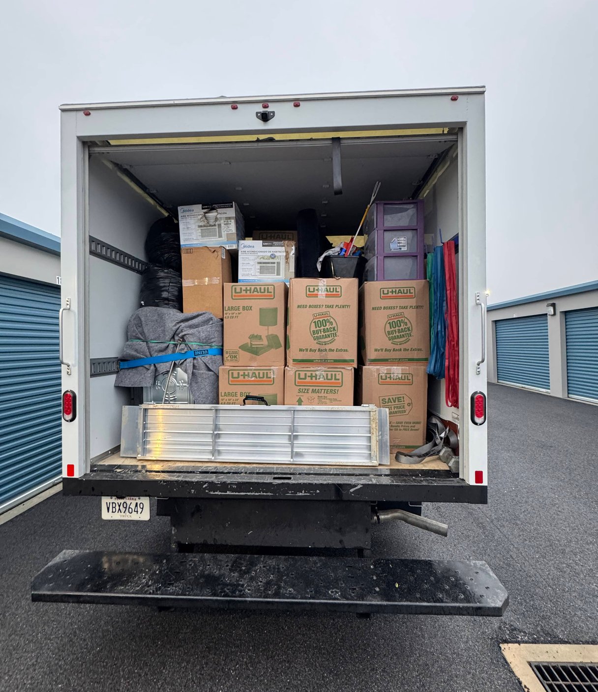 Two OneMove movers loading boxes into a customer's rental truck